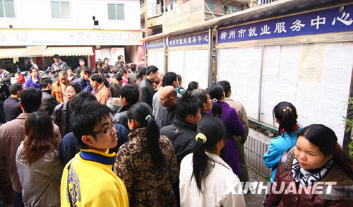 Migrant workers look at an information bulletin at a job fair in Liuzhou, Guangxi Zhuang Autonomous Region, on Feb. 20, 2010. Migrant workers go for job opportunities after spending the Spring Festival holidays in their hometowns.