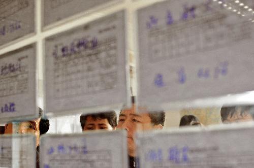 Migrant workers look at an information bulletin at a job fair in Hangzhou, capital of east China's Zhejiang Province, on Feb. 19, 2010.