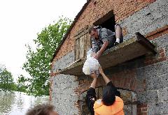 An emergency worker gives food suplies to a man in a flooded house in the village of Juliszew close to Plock in Central Poland May 24, 2010. [Xinhua/Reuters]