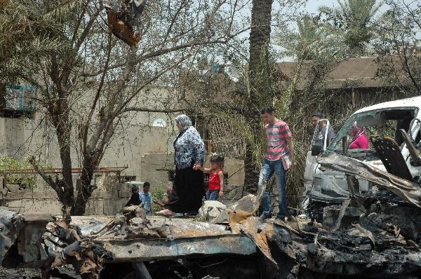 People walk past blast site in Baghdad, capital of Iraq, June 20, 2010. At least 33 people were killed and 54 were wounded in two car bomb explosions in western Baghdad on Sunday.[Xinhua] 