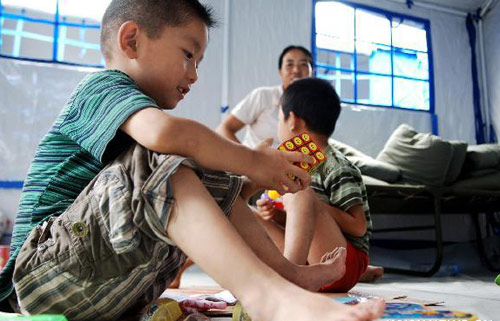 Six-year-old Geng Xin (L) plays with his brother in a temporary tent at a shelter place in mudslide-hit Zhouqu county, Gannan Tibetan autonomous prefecture in Northwest China&apos;s Gansu province, August 12, 2010. [Xinhua]