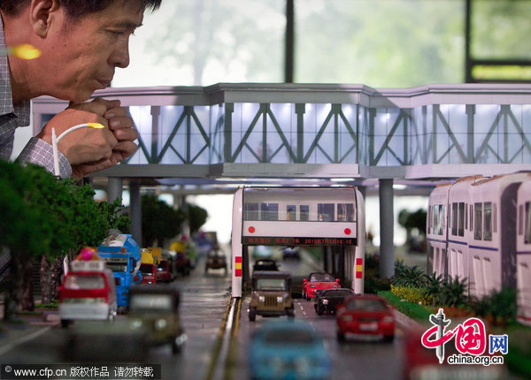 Song Youzhou, Chairman of Shenzhen Huashi Future Parking Equipment Co. Ltd. poses next to his invention, a scale model of &apos;straddle bus&apos;, at an office showroom in Beijing, Friday, Sept. 3, 2010. [CFP]