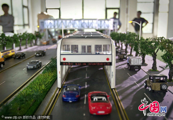 visitors looks at a scale model of &apos;straddle bus&apos;. The &apos;straddle bus&apos;, invented by Shenzhen Huashi Future Parking Equipment Co. Ltd., on display at an office showroom in Beijing, Friday, Sept. 3, 2010. [CFP]