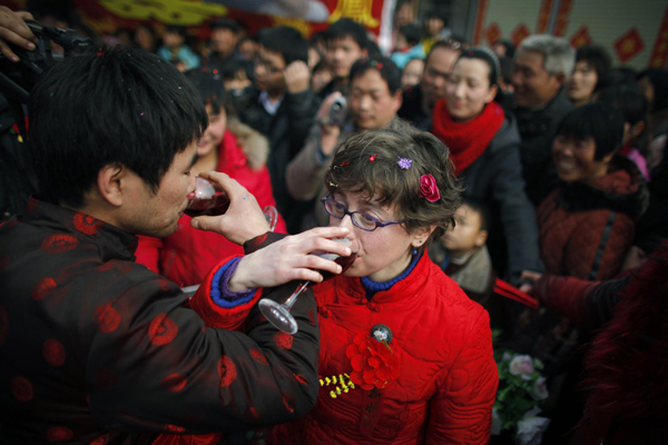 Rebecca Kanthor (R) and Liu Jian (L) drink red wine as part of their traditional Chinese wedding in Dong&apos;an at the central province of Henan, February 9, 2011. [China Daily/Agencies]