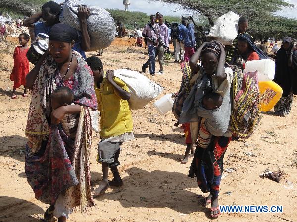 People leave homes for a new camp due to drought in the southwestern outskirts of Mogadishu, capital of Somalia, July 12, 2011. Hundreds of people arrived in government-controlled Mogadishu each day to seek food and shelter. [Faisal Isse/Xinhua] 