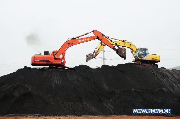 Excavators remove iron ore at the port of Qingdao, a coastal city in east China's Shandong Province, Sept. 7, 2011. 