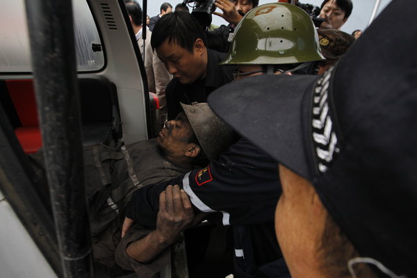 A trapped miner is rescued on Friday a day after a rock burst in Qianqiu Coal Mine, Henan Province. The accident stranded 75 miners in the shaft and killed at least eight out of them. [CFP]