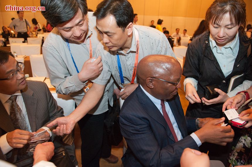 Chinese attendants to the South African Day event exchange business cards with Cao Jiachang (L), vice director of Department of Western Asian and African Affairs, China&apos;s Ministry of Commerce, and Dr. Langa, South Africa&apos;s ambassador to China (R) for more information to invest in South Africa. [Photo / Chen Boyuan]