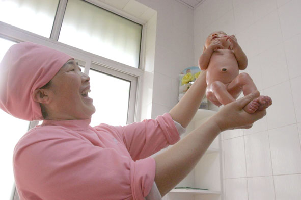 A midwife holds a newborn infant at a hospital in Quzhou, East China's Zhejiang province on April 28, 2014. [File photo] 